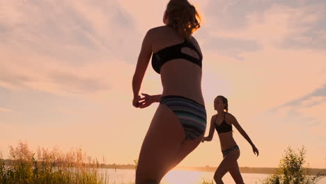 Gruppe-Junger-Mädchen,-Die-Beachvolleyball-Bei-Sonnenuntergang-Oder-Sonnenaufgang-In-Zeitlupe-Spielen.-Schöne-Mädchen-Im-Bikini-Spielen-Professionell-Volleyball-Auf-Dem-Sand